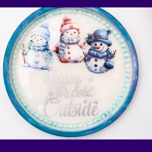 Round AquaCast resin snowman tray with three illustrated snowmen and “Baby it’s cold outside” text.