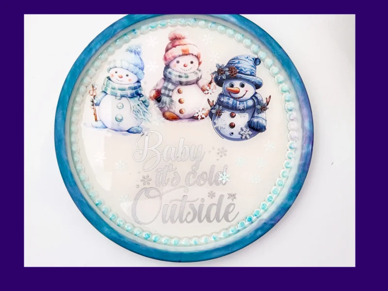 01_Hero Round AquaCast resin snowman tray with three illustrated snowmen and “Baby it’s cold outside” text.