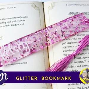 Pink heart-shaped glitter bookmark personalised with the name Kelsey, displayed on an open book with a matching pink tassel.