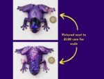 9. kirnix scale โTwo resin frog variantsโsmooth purple and glitter purpleโeach shown beside a ยฃ1 coin to show size.โ