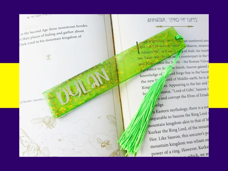 Green glitter bookmark personalised with the name Dylan, placed across the pages of an open book with a bright green tassel