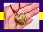 KC-ATP-045E-002_007 Heart-shaped resin pendant with yellow tree-of-life wire wrapping displayed in hand โ earthy, nature inspired handmade necklace