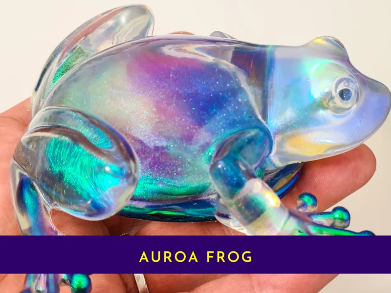 Close-up of the handmade aurora resin frog held in hand to show its colour-shifting detail.