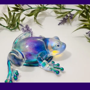 Aurora-shimmer resin frog displayed with green leaves and lavender accents.