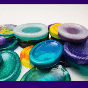 Close-up of several handmade resin calming stones stacked in a row, showing the variety available in the Chaos Solo lucky dip.