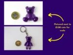 Purple resin Worry Bear handheld and keyring style shown next to £1 coin for size comparison