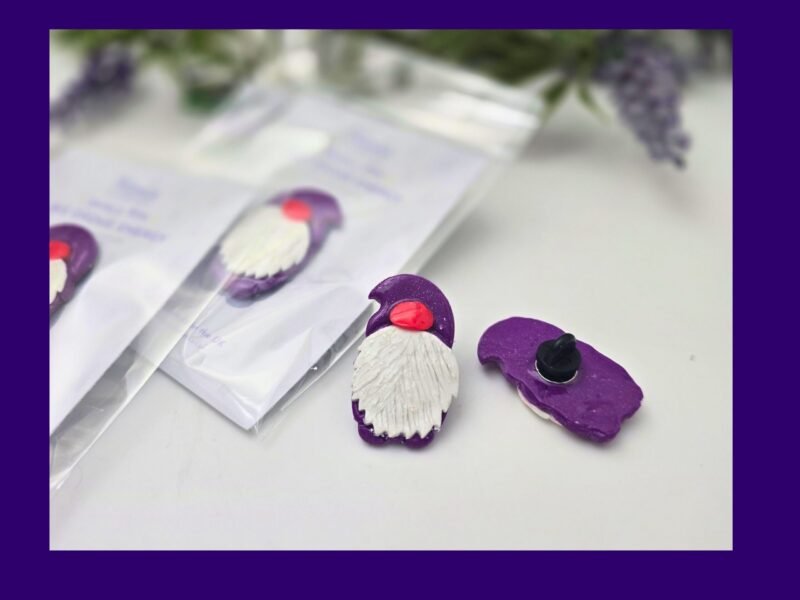Packaged purple gnome pin on Kirnix Creations backing card inside a clear sleeve, shown front-on