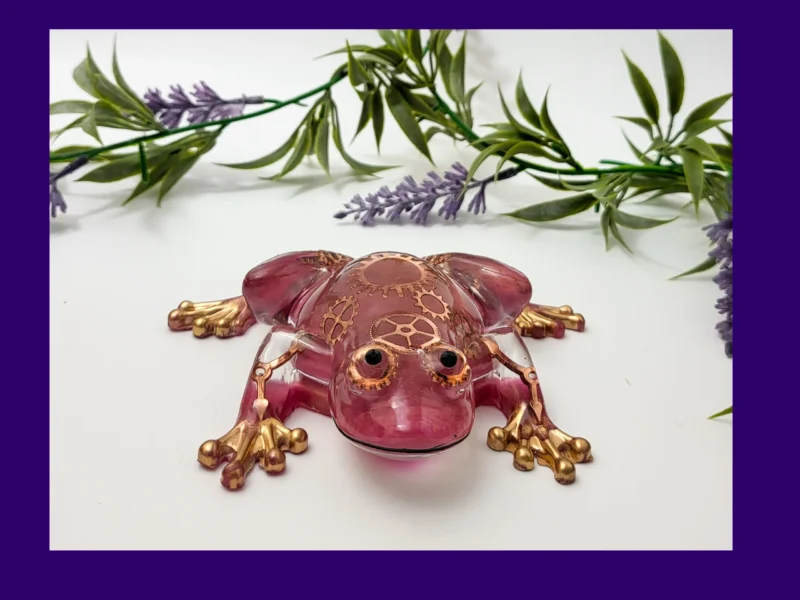 Front view of handmade steampunk resin frog with metallic gears and gold-painted toes.