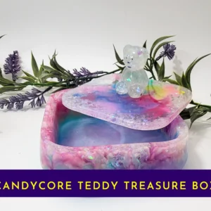 Open pastel rainbow resin treasure box with teddy-topped lid resting on the rim; banner text reads “Candycore Teddy Treasure Box”.