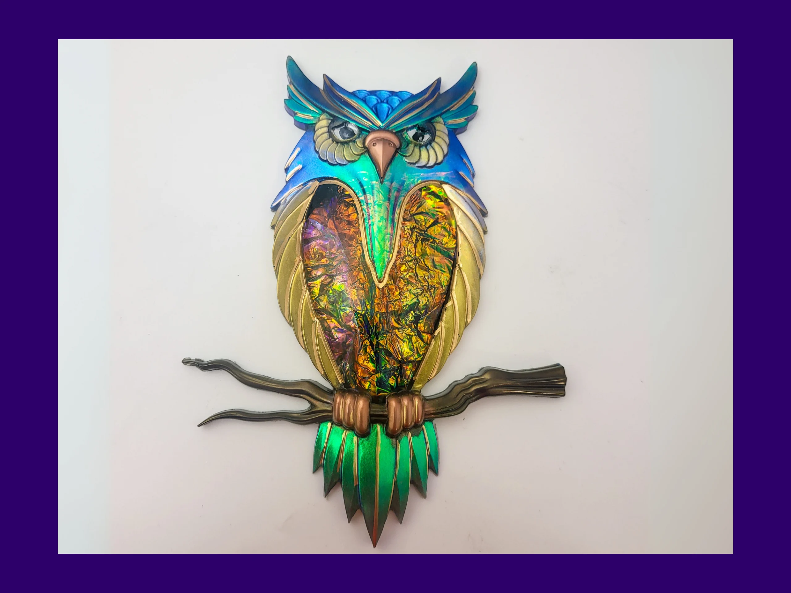 Full view of “The Starlit Sentinel” owl décor on a white background, featuring blue-green shimmer, gold wings, rainbow foil chest, and a bronze branch.