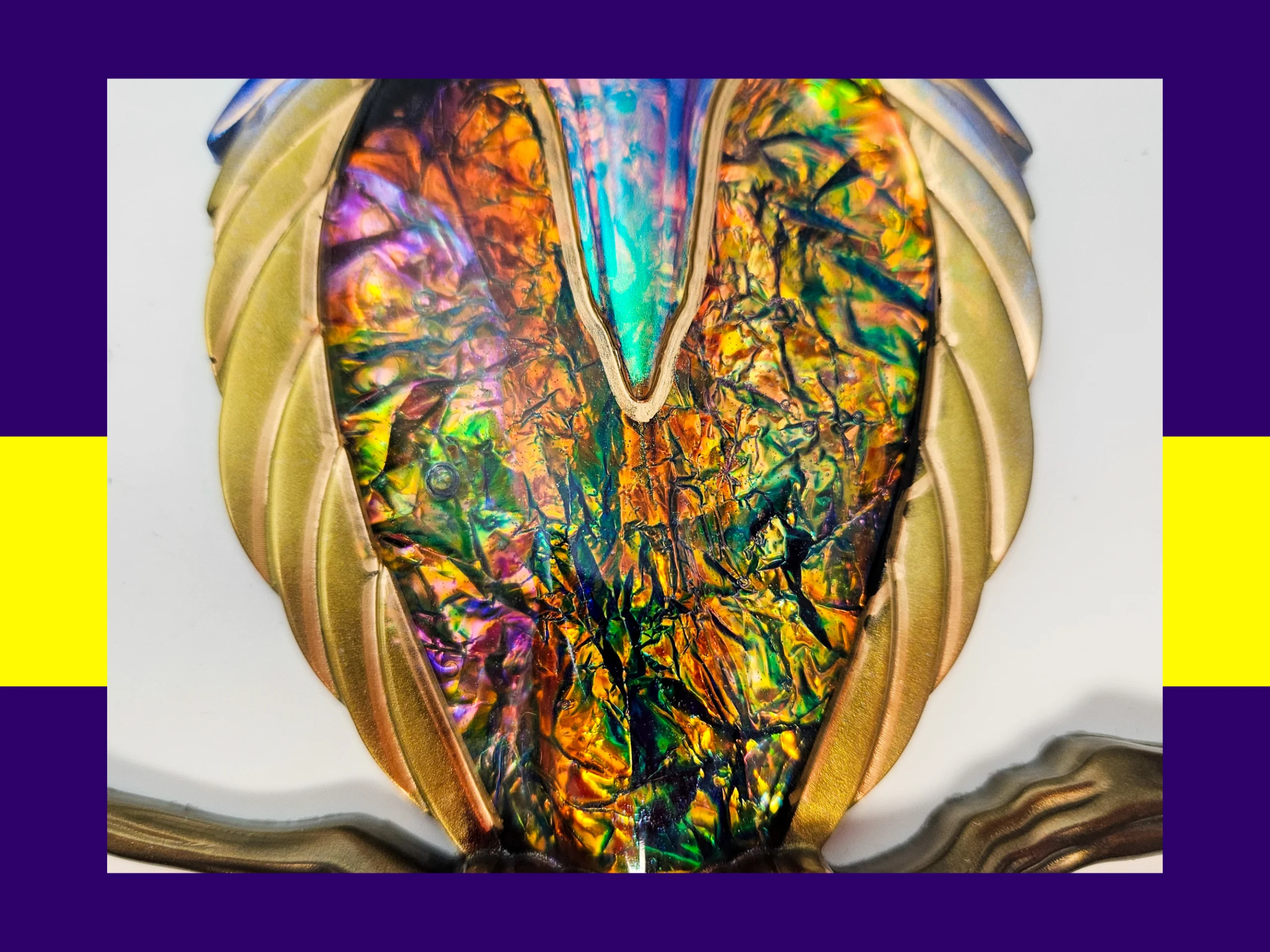 Close-up of the owl’s chest area showing crinkled rainbow iridescent foil framed by gold feather detailing.