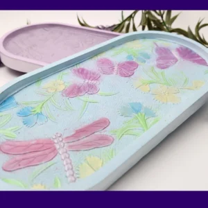 “Front view of pastel resin trinket tray featuring raised dragonflies, butterflies and floral details.”