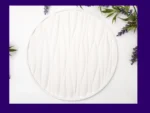 KC-TRAY-WAVE-RND-00103_Real-Photo White round tray with raised wave texture photographed flat lay with greenery and lavender around the edges, framed by a purple border.