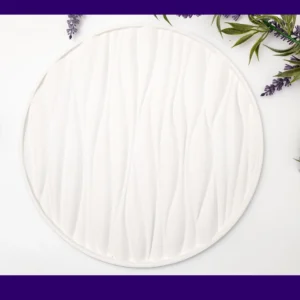 White round tray with raised wave texture photographed flat lay with greenery and lavender around the edges, framed by a purple border.
