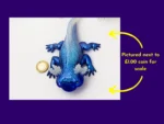 KNC-AXO-ICE-00107_Coin-Scale Ice axolotl photographed beside a ยฃ1 coin for scale with explanatory text.