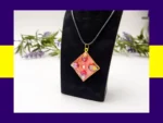 OOO-UVR-001_004 Red-toned square resin petal pendant necklace displayed on a black jewellery stand.