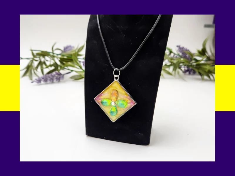 Pink square resin petal pendant necklace displayed on a black jewellery stand.