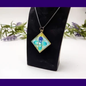 Teal square resin petal pendant necklace displayed on a black jewellery stand