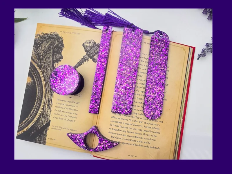 01_Hero Purple glitter bookmark set laid out on an open book showing all five styles together.