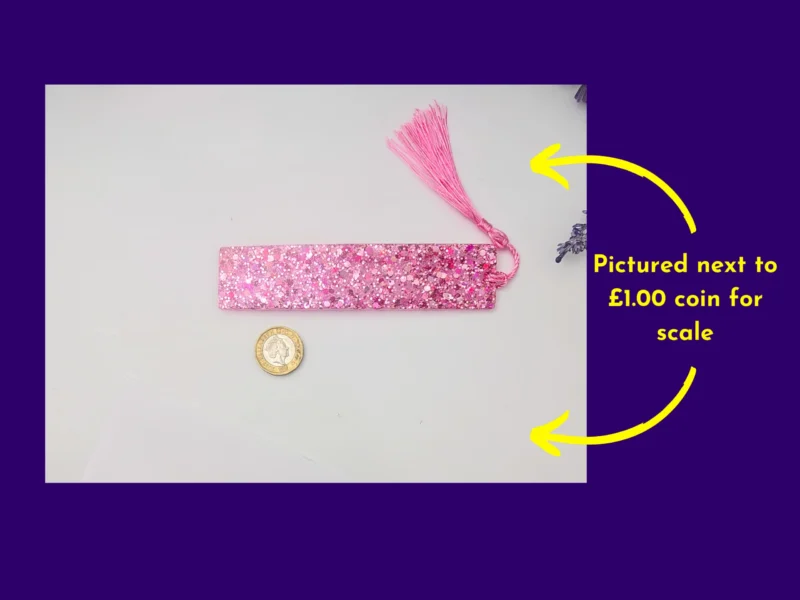 Pink glitter bookmark and tassel beside a coin for scale, with arrows showing coin reference.