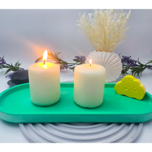 gREEN extra large oval catchall tray styled with two lit pillar candles on a tabletop.