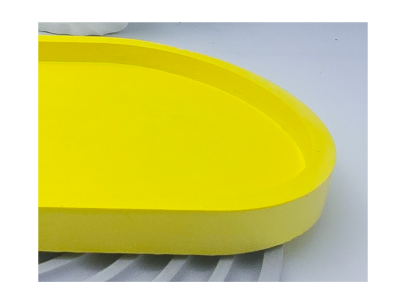 Close-up side view of a yellow oval tray showing the raised edge and profile.