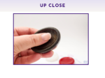 Black and red resin worry stones shown up close being held in a hand.