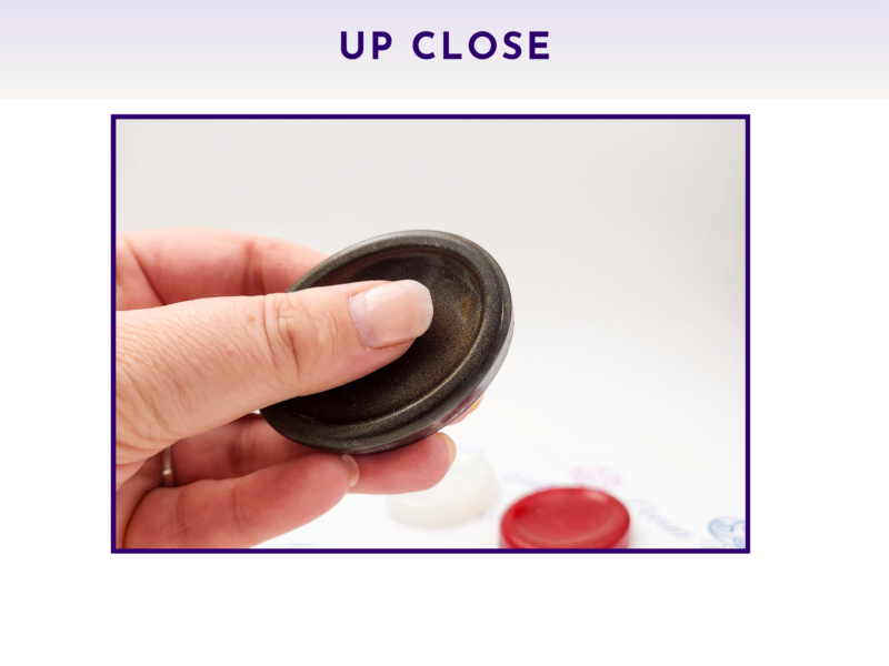 Black and red resin worry stones shown up close being held in a hand.