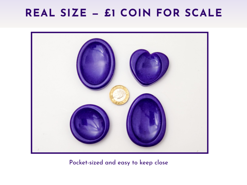Purple resin worry stones shown beside a £1 coin for size comparison.
