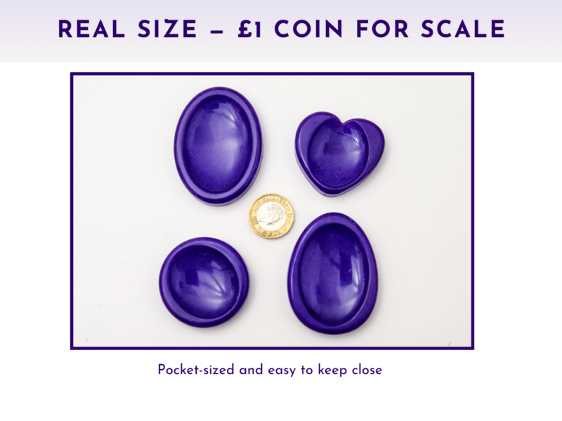 Purple resin worry stones shown beside a £1 coin for size comparison.