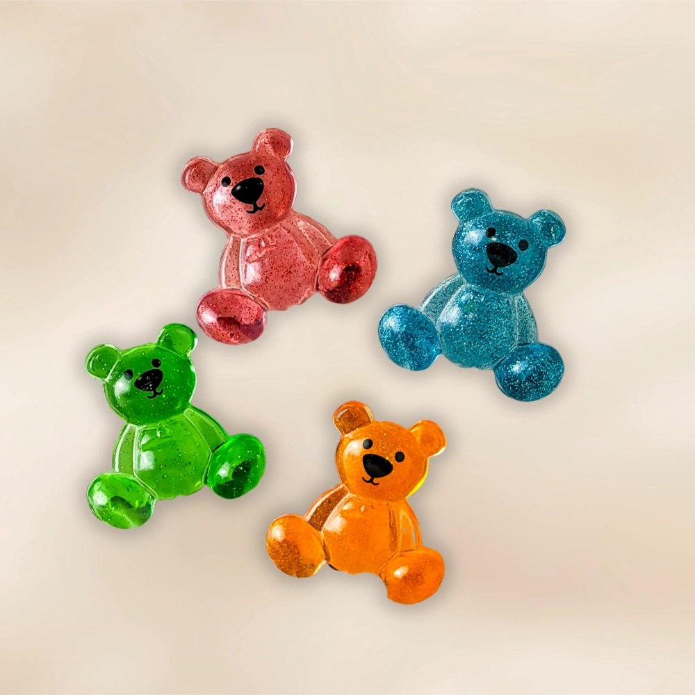Four glitter resin bear pocket companions in red, teal, green and orange on a warm neutral backdrop.
