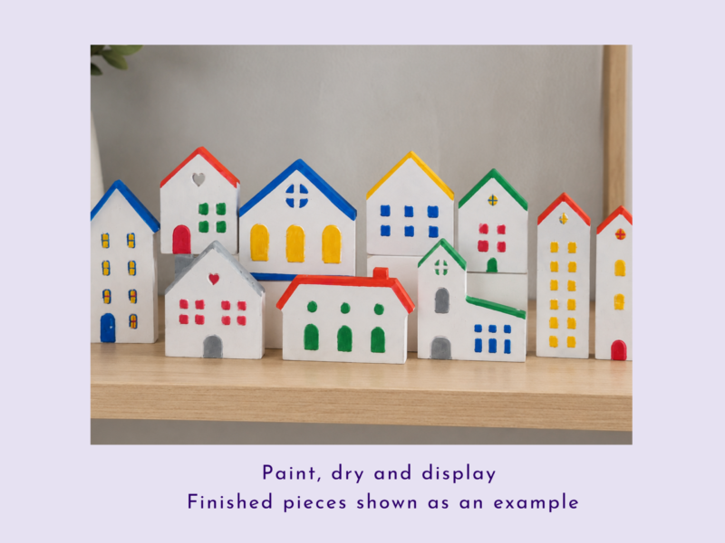 Row of colorful painted wooden toy houses arranged on a wooden shelf, each with bright roofs and windows.