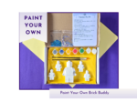 Hero product image showing a boxed paint your own brick buddy kit with two blank figures, paint pots and instructions