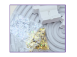 Close-up of a transparent gift bag filled with silver star-shaped confetti beside pale wrapped boxes on a gray surface.