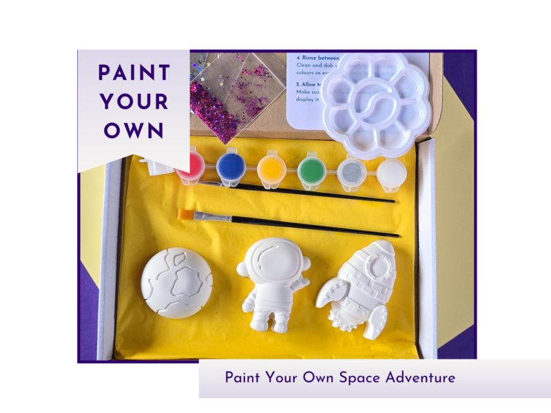 Hero product image showing a boxed paint your own space adventure kit with blank astronaut, rocket and planet shapes, paint pots and glitter