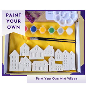 Paint your own mini village kit showing white house figures, paints, brush, palette and kit packaging on a yellow background.