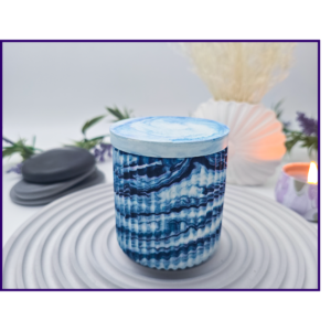 Small blue and white marbled storage pot with lid styled on a striped surface with neutral décor