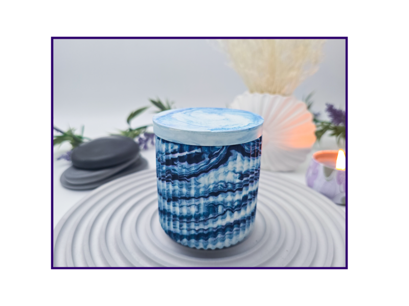 Small blue and white marbled storage pot with lid styled on a striped surface with neutral décor