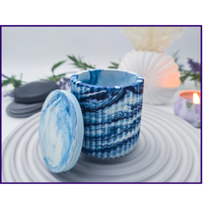 Blue and white marbled storage pot with the lid resting beside it on a striped surface