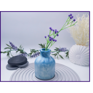 Blue and white marbled decorative bud vase styled with lavender stems on a striped surface with neutral décor