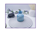 Decorative bud vase in blue and white marble shown on a striped surface beside black stones and neutral styling props