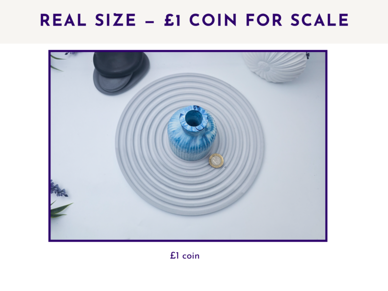 Poster announcing real size with a £1 coin for scale; photo shows a blue ceramic vase on a coiled cord with coins nearby.