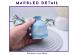 Hand holding the decorative bud vase close up to show the blue and white marbled detail