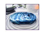 Small oval marbled tray on a striped surface beside black stones and dried stems