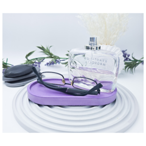 Perfume bottle resting on a purple flip-flop, with glasses laid over the sandal and botanical décor in the background.