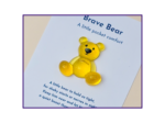 Yellow teddy bear on a page that reads 'Brave Bear: A little pocket comfort' with purple border framing the image.