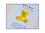 Yellow teddy bear on a page that reads 'Brave Bear: A little pocket comfort' with purple border framing the image.