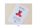 Tilted white card on a beige background featuring a red glittery bear and the title 'Brave Bear'