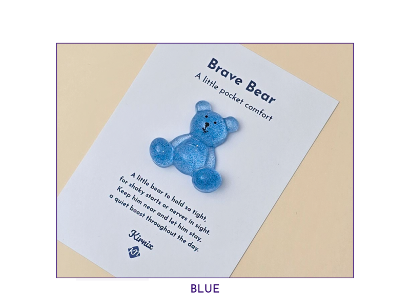 Blue teddy bear on a white card titled 'Brave Bear' with a pocket comfort message; BLUE caption below edge.