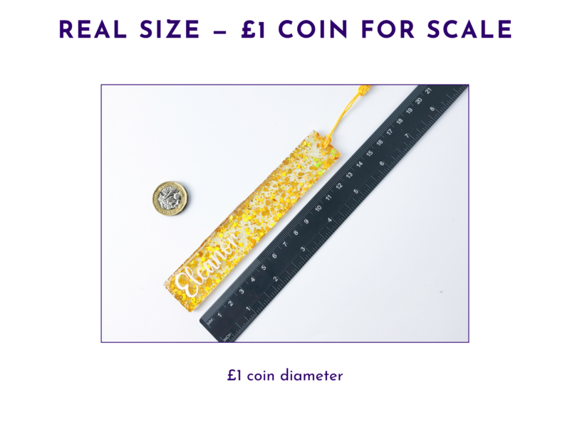 Glittery gold rectangular pendant next to a black ruler for scale, with a UK one-pound coin nearby for reference.